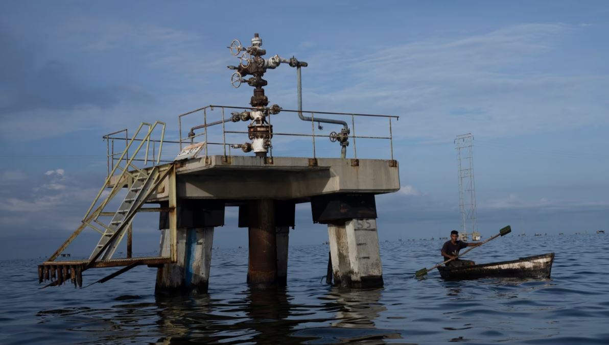 ARCHIVO - Un pescador navega cerca de una instalación petrolera en el Lago de Maracaibo, en el occidente de Venezuela, el 12 de octubre de 2022.