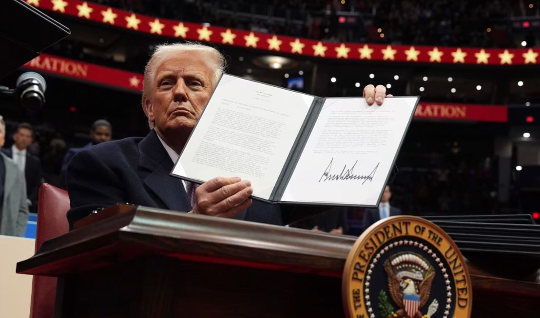 El presidente Donald Trump firma una orden ejecutiva mientras asiste a un desfile inaugural presidencial en el Capital One Arena, el 20 de enero de 2025, en Washington.